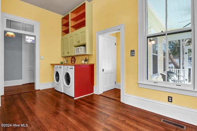 washroom with dark hardwood / wood-style flooring, cabinets, and washer and dryer