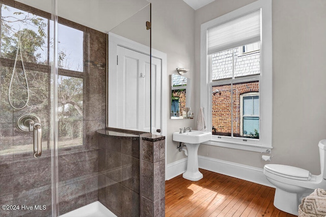 bathroom featuring hardwood / wood-style flooring, a shower with door, and plenty of natural light