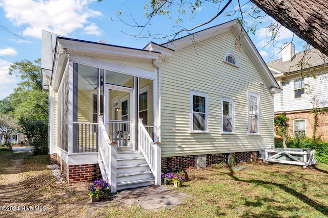 back of property featuring a sunroom and a yard