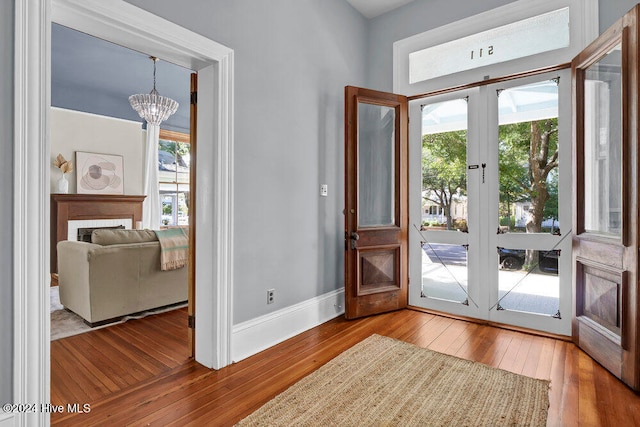 doorway featuring a chandelier, a healthy amount of sunlight, light hardwood / wood-style flooring, and french doors