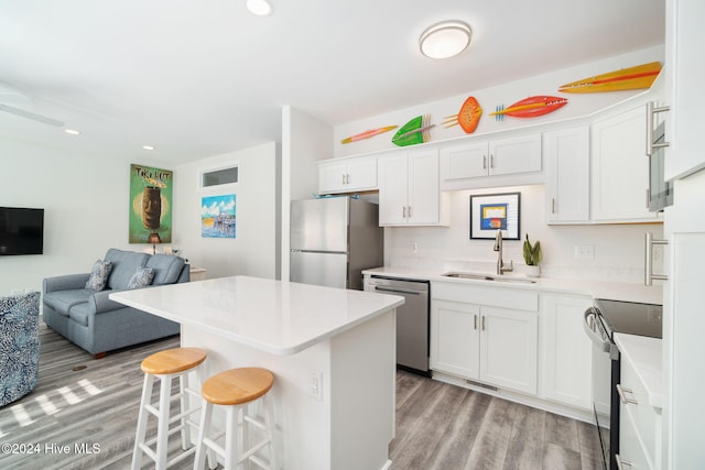 kitchen featuring sink, stainless steel appliances, a center island, and white cabinets