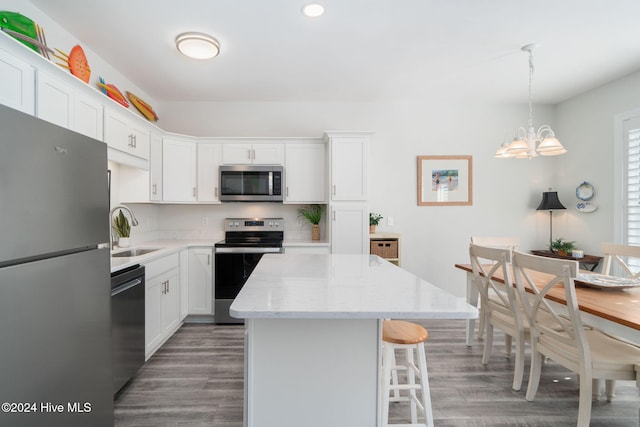 kitchen with appliances with stainless steel finishes, a center island, hanging light fixtures, and white cabinets