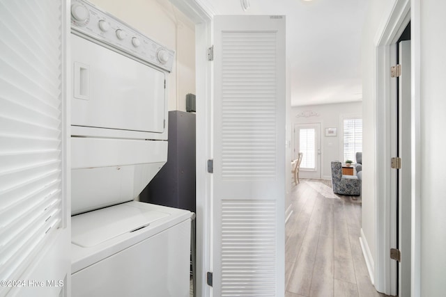 clothes washing area featuring light hardwood / wood-style flooring and stacked washer and clothes dryer