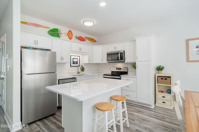 kitchen with sink, a breakfast bar, white cabinetry, stainless steel appliances, and a center island