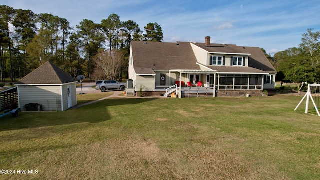 rear view of house featuring a shed, a lawn, and a sunroom