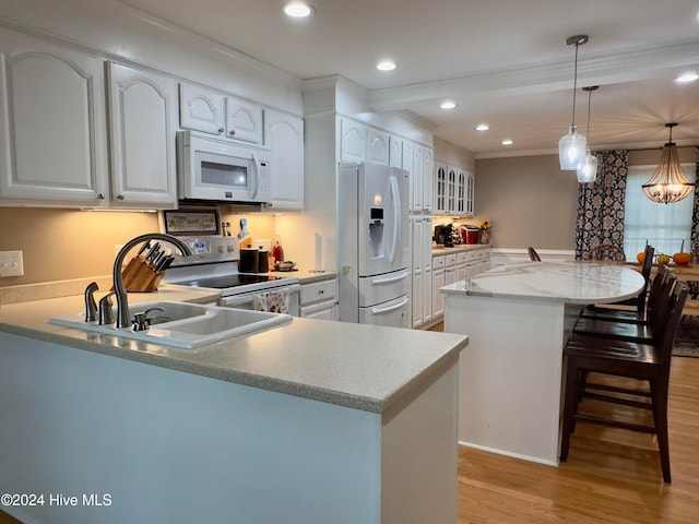 kitchen with sink, white cabinetry, light wood-type flooring, appliances with stainless steel finishes, and decorative light fixtures