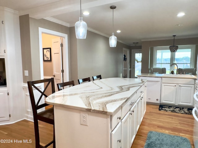 kitchen with a kitchen island, white cabinetry, light hardwood / wood-style floors, and a breakfast bar