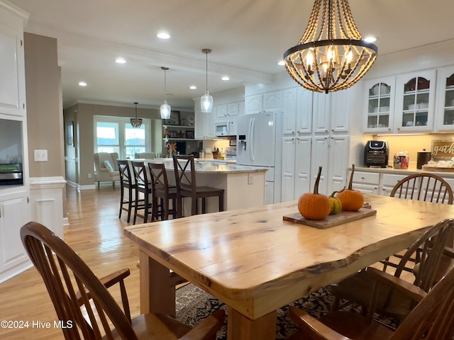 dining area featuring ornamental molding, a notable chandelier, and light hardwood / wood-style floors