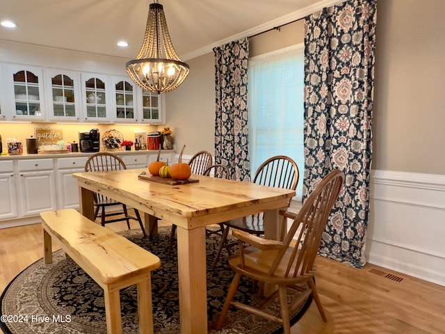 dining space featuring ornamental molding, light hardwood / wood-style floors, and a notable chandelier