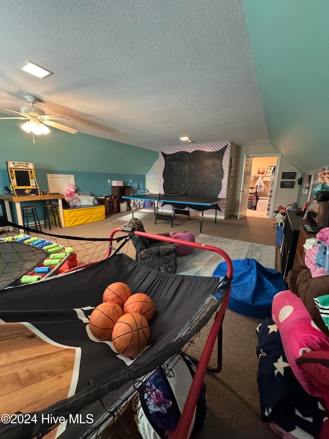 recreation room with carpet, a textured ceiling, and vaulted ceiling