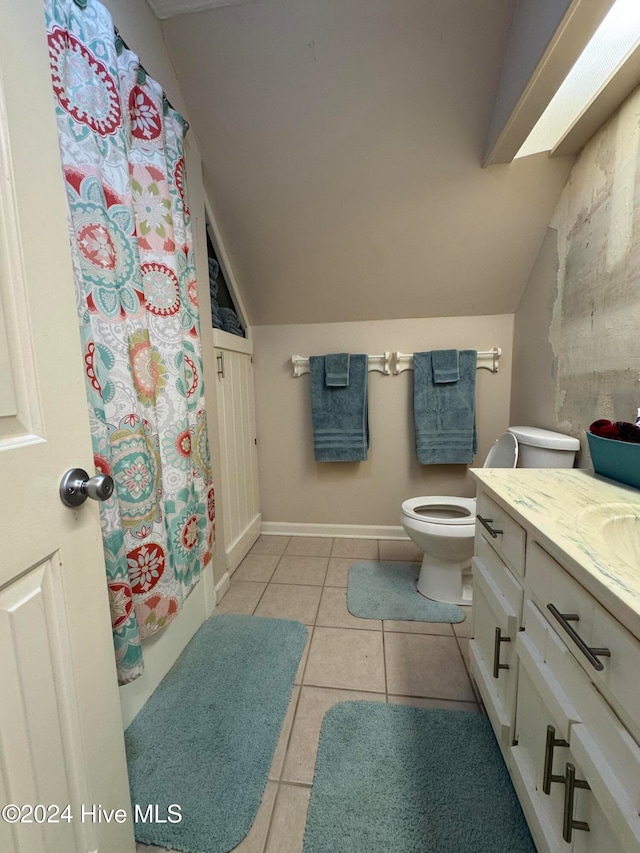 bathroom with toilet, vanity, tile patterned floors, and vaulted ceiling