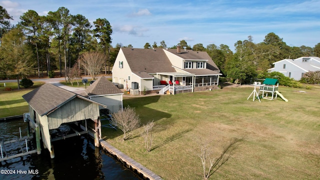 back of property with a water view and a lawn