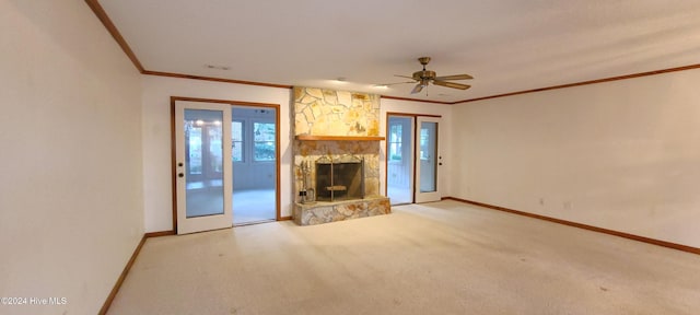 unfurnished living room featuring ceiling fan, a stone fireplace, light carpet, and ornamental molding