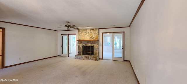 unfurnished living room with a stone fireplace, light carpet, ceiling fan, and crown molding