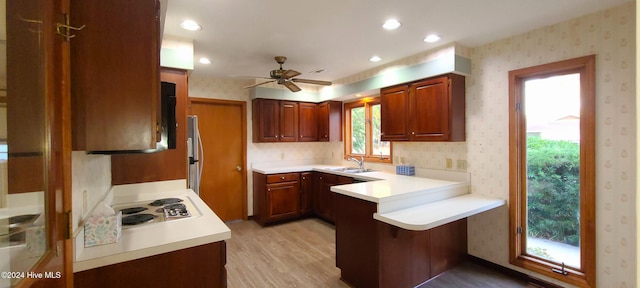 kitchen featuring light hardwood / wood-style floors, white gas stovetop, kitchen peninsula, sink, and stainless steel fridge