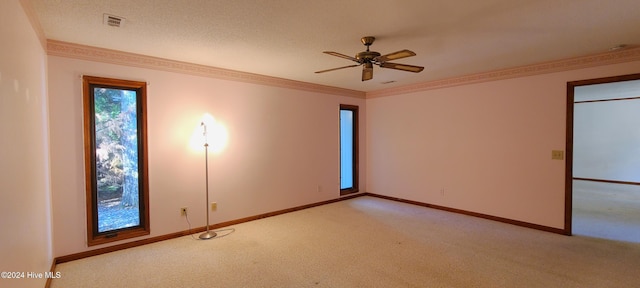 carpeted spare room featuring a textured ceiling, ceiling fan, and crown molding