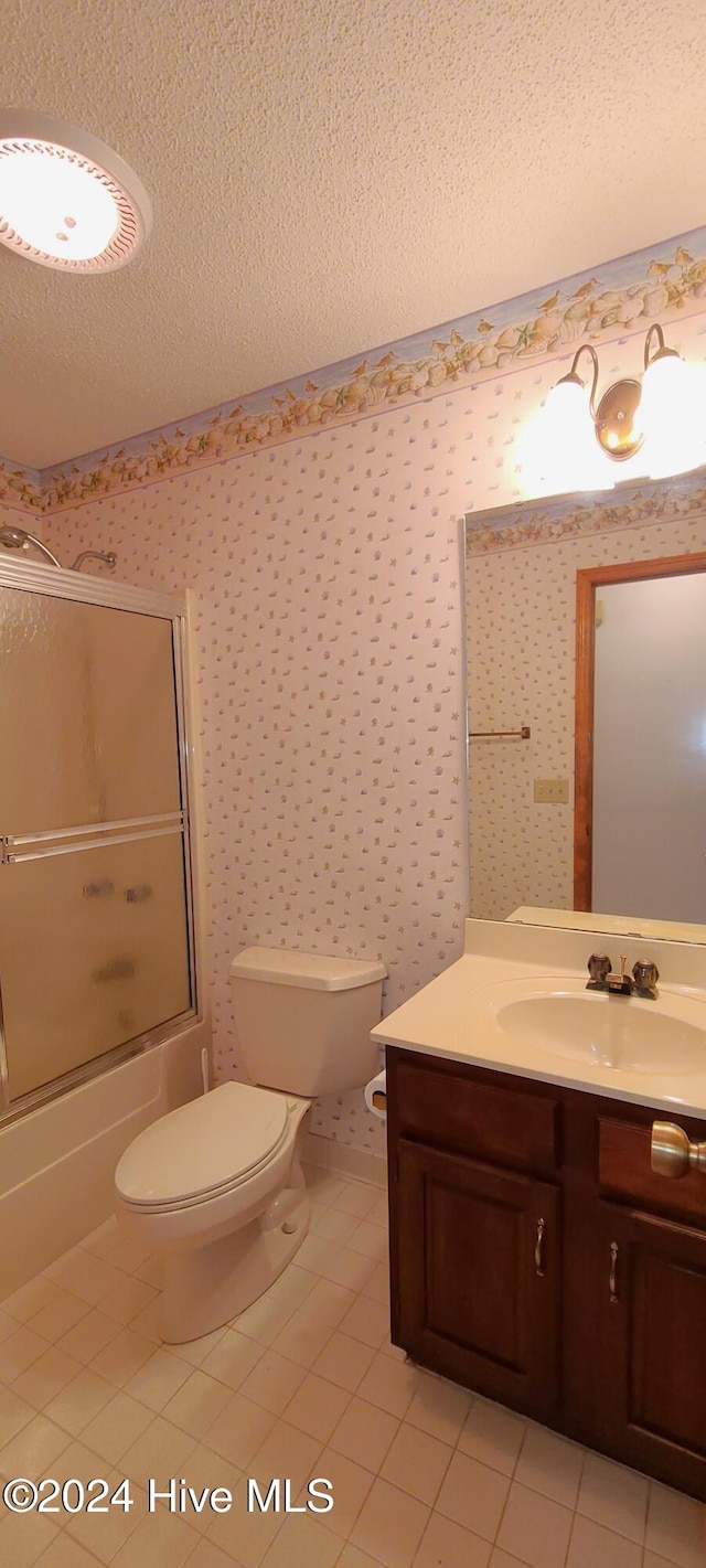 full bathroom featuring enclosed tub / shower combo, toilet, tile patterned floors, a textured ceiling, and vanity