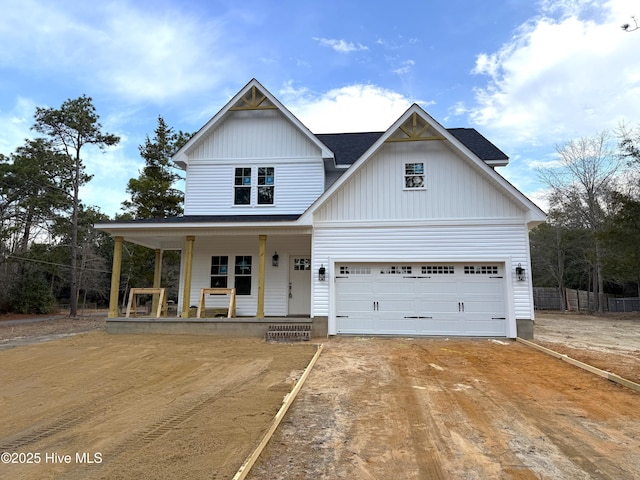 view of front facade featuring driveway, a shingled roof, and a porch