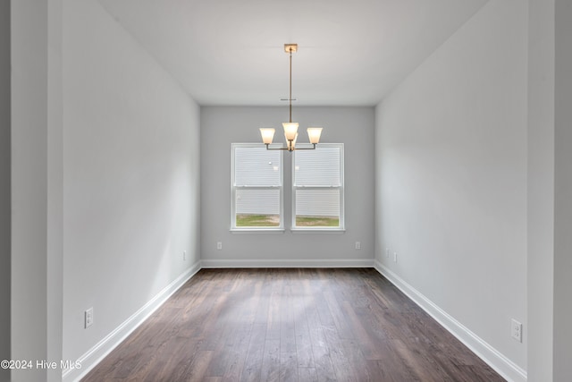 unfurnished room featuring dark wood-type flooring and a chandelier