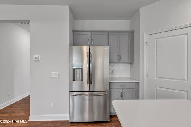 kitchen with stainless steel refrigerator with ice dispenser, gray cabinetry, decorative backsplash, and dark hardwood / wood-style flooring