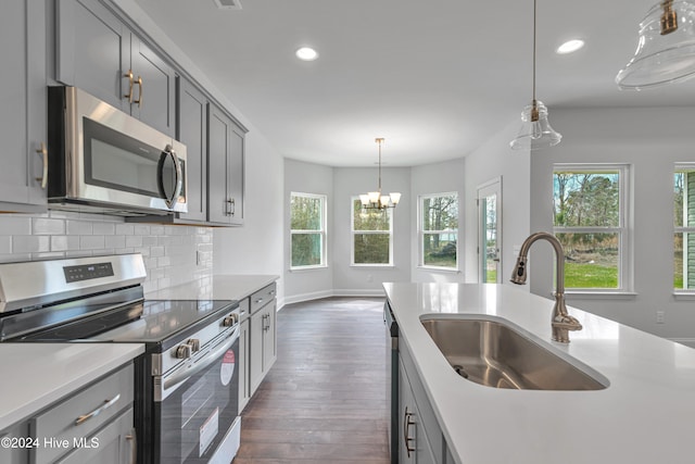 kitchen with hanging light fixtures, sink, gray cabinetry, dark hardwood / wood-style floors, and appliances with stainless steel finishes