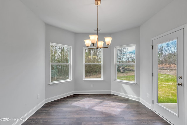 unfurnished dining area featuring a notable chandelier, a healthy amount of sunlight, and dark hardwood / wood-style floors