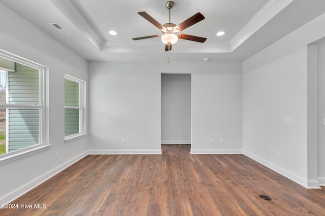 spare room with dark hardwood / wood-style flooring, ceiling fan, ornamental molding, and a raised ceiling