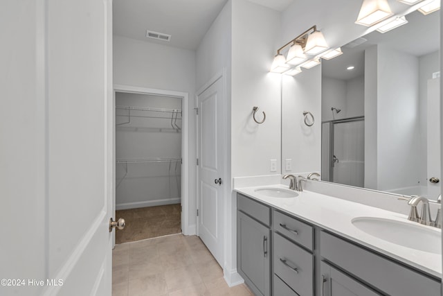 bathroom with a shower with door, vanity, and tile patterned floors