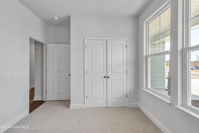 unfurnished bedroom featuring light carpet and a closet