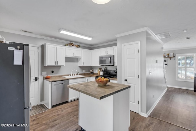 kitchen featuring white cabinetry, sink, appliances with stainless steel finishes, a center island, and wood counters