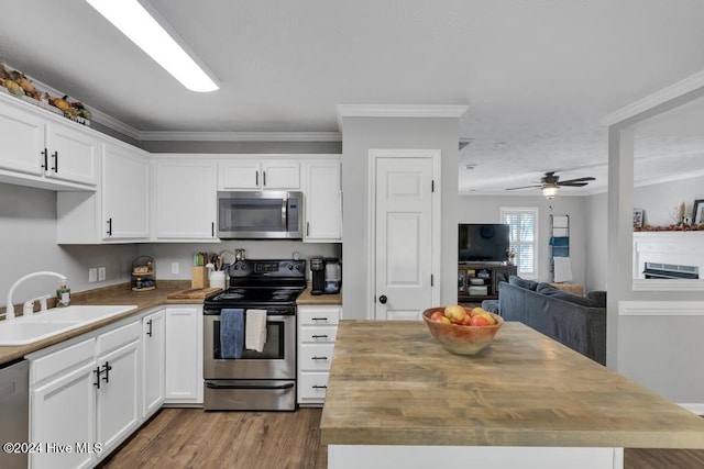 kitchen with ornamental molding, stainless steel appliances, hardwood / wood-style floors, sink, and white cabinets