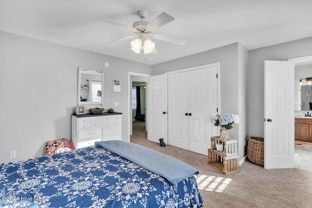 carpeted bedroom featuring a closet, ceiling fan, and ensuite bathroom