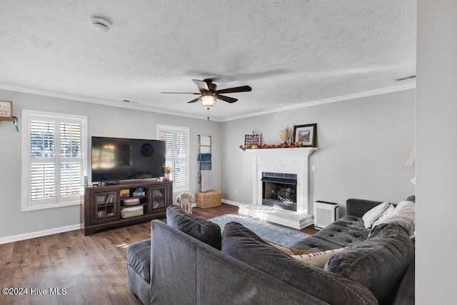 living room featuring ceiling fan, wood-type flooring, a healthy amount of sunlight, and crown molding