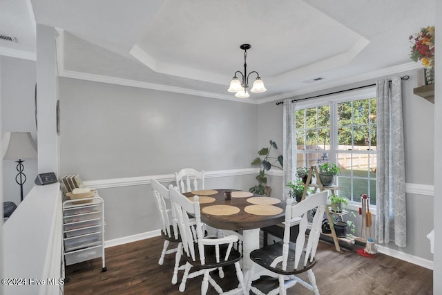 dining space featuring dark wood-type flooring, a tray ceiling, and crown molding