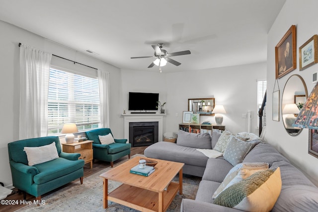 living room featuring hardwood / wood-style floors, a tile fireplace, and ceiling fan