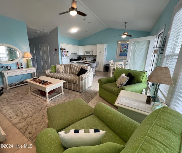 living room featuring ceiling fan, light tile patterned floors, and vaulted ceiling