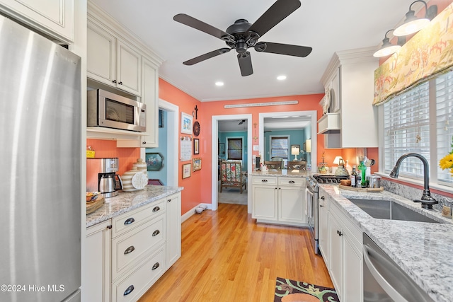 kitchen with light hardwood / wood-style floors, stainless steel appliances, sink, crown molding, and white cabinetry