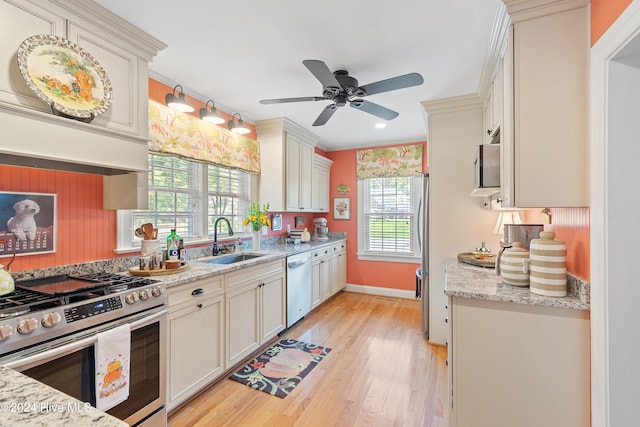 kitchen featuring light wood-type flooring, appliances with stainless steel finishes, sink, and light stone countertops