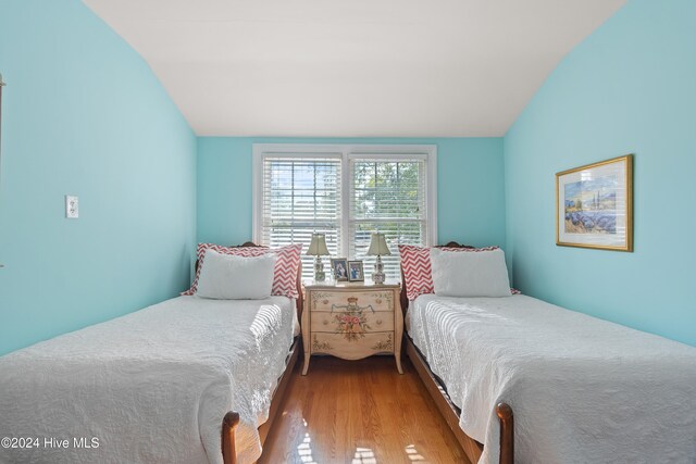 bedroom featuring light wood-type flooring and vaulted ceiling