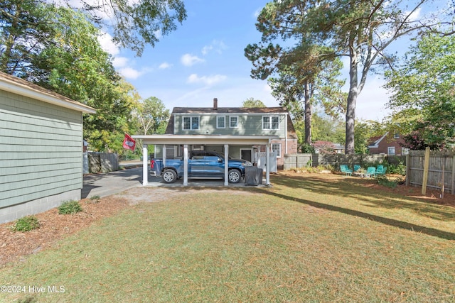 rear view of property featuring a lawn and a carport