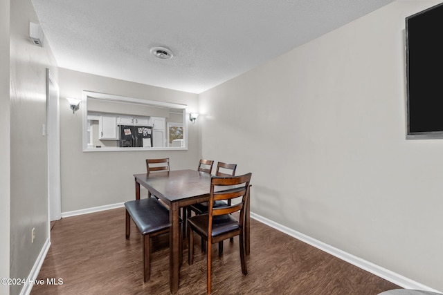 dining area featuring dark wood-type flooring and a textured ceiling