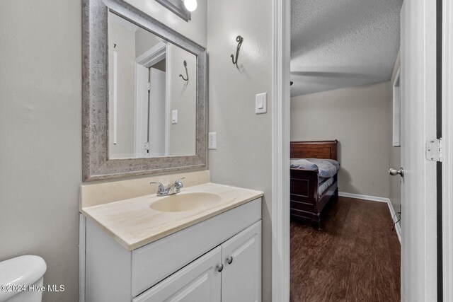 bathroom featuring hardwood / wood-style floors, vanity, toilet, and a textured ceiling