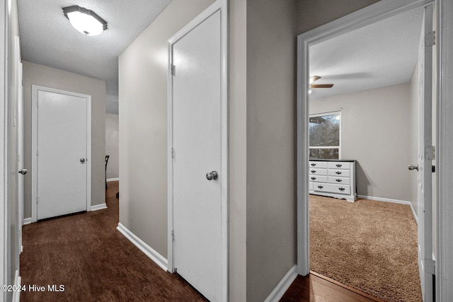 corridor featuring dark wood-type flooring and a textured ceiling