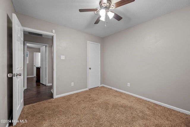 unfurnished bedroom with dark colored carpet and ceiling fan