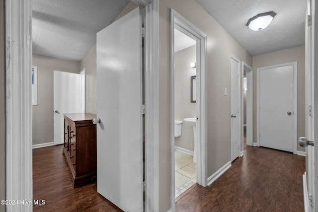 hallway with a textured ceiling and dark hardwood / wood-style floors