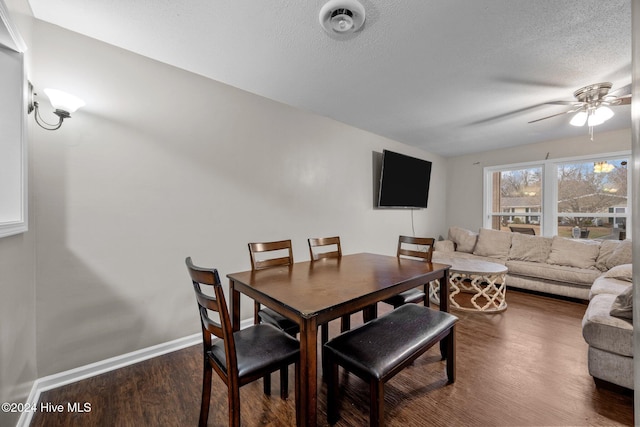 dining area with ceiling fan, dark wood-type flooring, and a textured ceiling