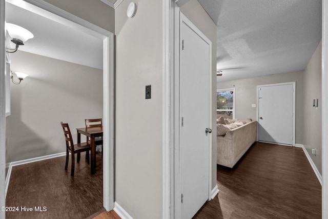 hall featuring dark wood-type flooring and a textured ceiling