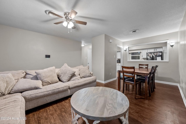 living room featuring a textured ceiling, ceiling fan, and dark wood-type flooring