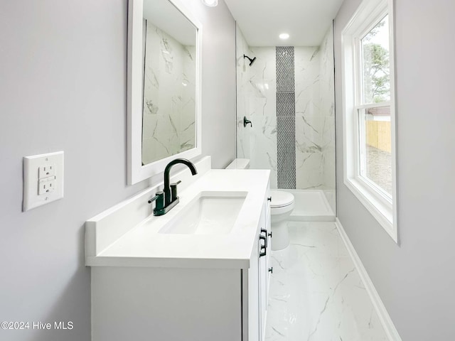 bathroom with toilet, vanity, and a tile shower