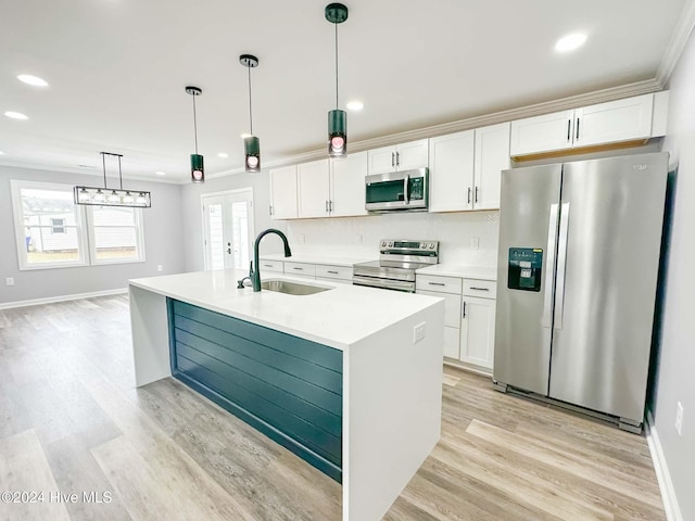 kitchen with stainless steel appliances, white cabinetry, sink, decorative light fixtures, and a kitchen island with sink